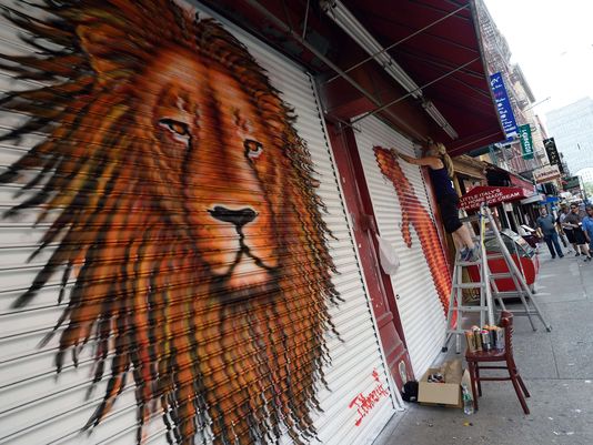 Artist J. Morello, after completing a painting of Cecil the Lion, works on another painting on a store front in New York. © Don Emmert, AFP/Getty Images