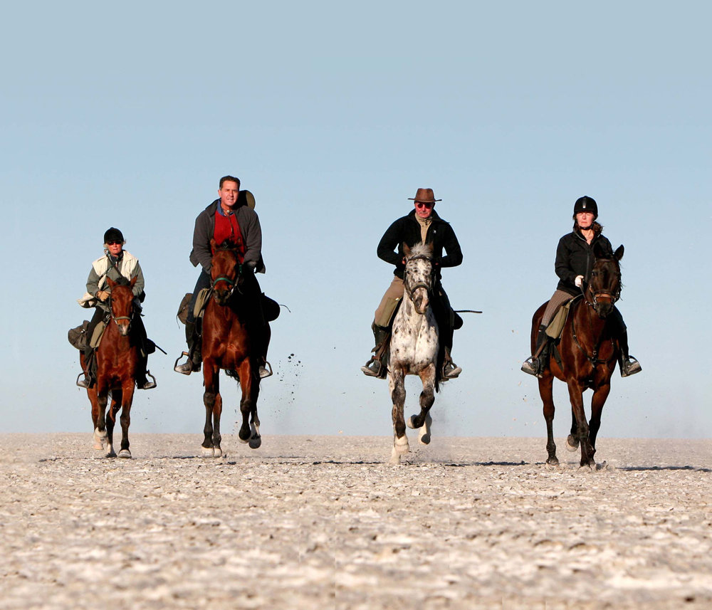A group of people riding on horseback across the salt pans