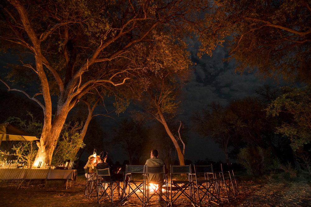 Two people sitting around a campfire