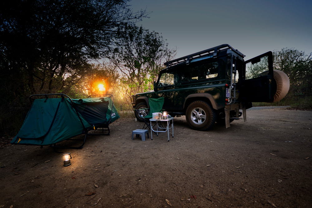 A tent-cot, camping table and 4x4 vehicle in Kruger National Park, South Africa