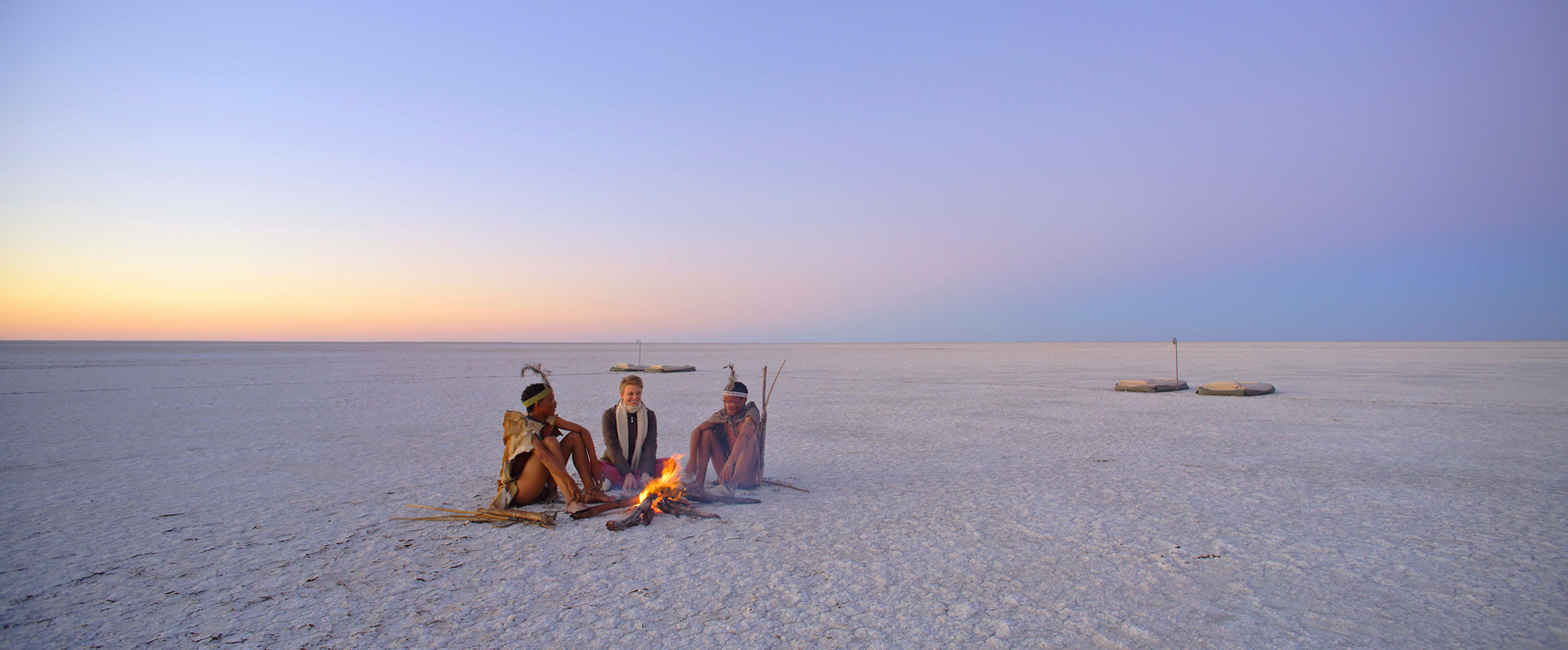 Khoisan and guest sitting in salt pan in Botswana