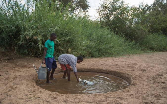 Children collecting water from dry riverbed in Mfuwe in Zambia