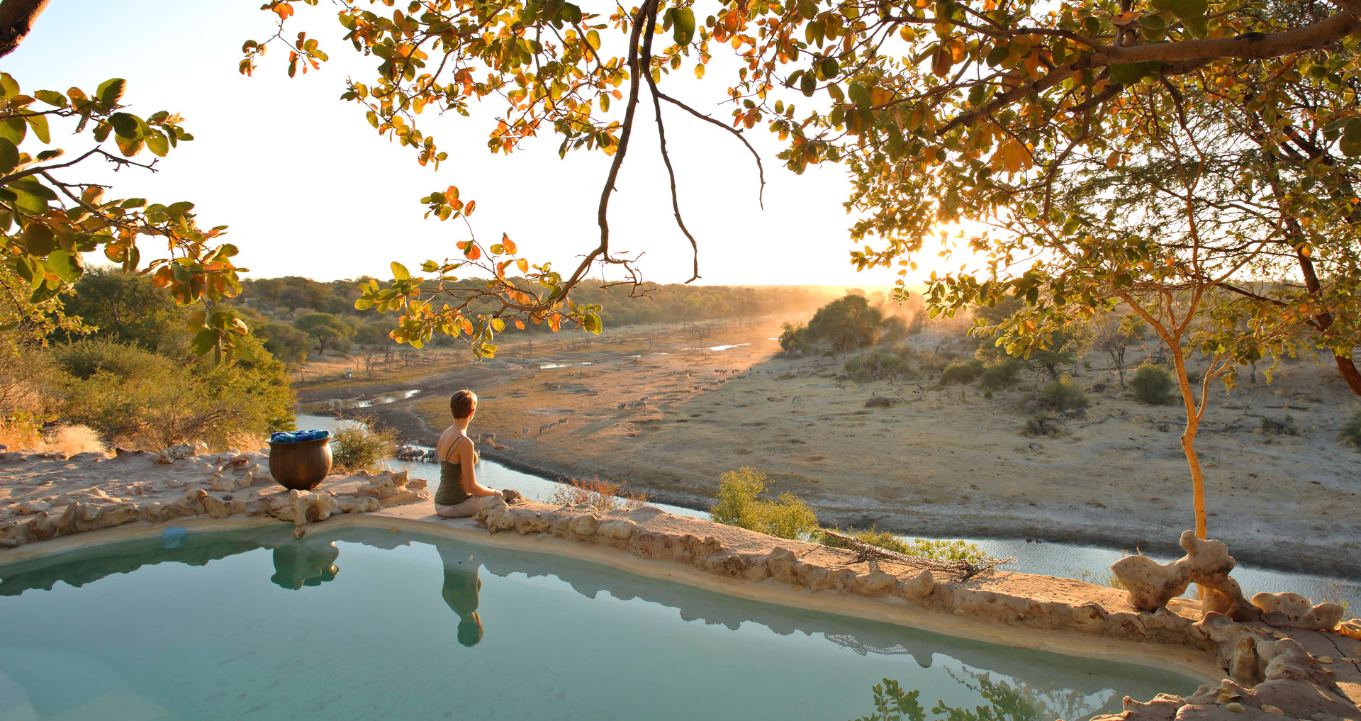 Person watching sunset from pool in Meno a Kwena, Botswana