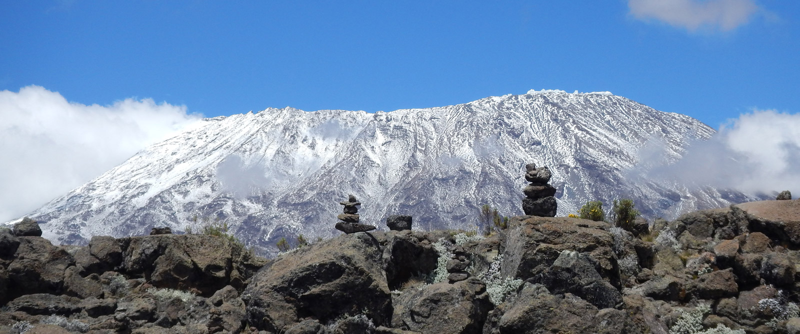 Rock cairns dwarfed by Mount Kilimanjaro in the distance © Shelley Hyne