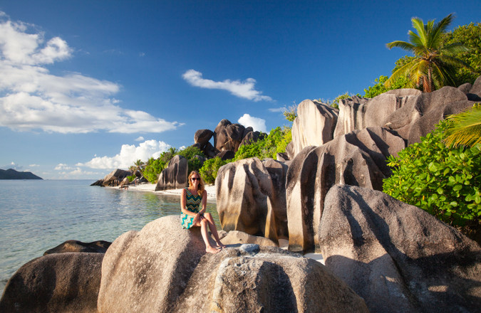 Visitor sitting on rocks on La Digue, Seychelles