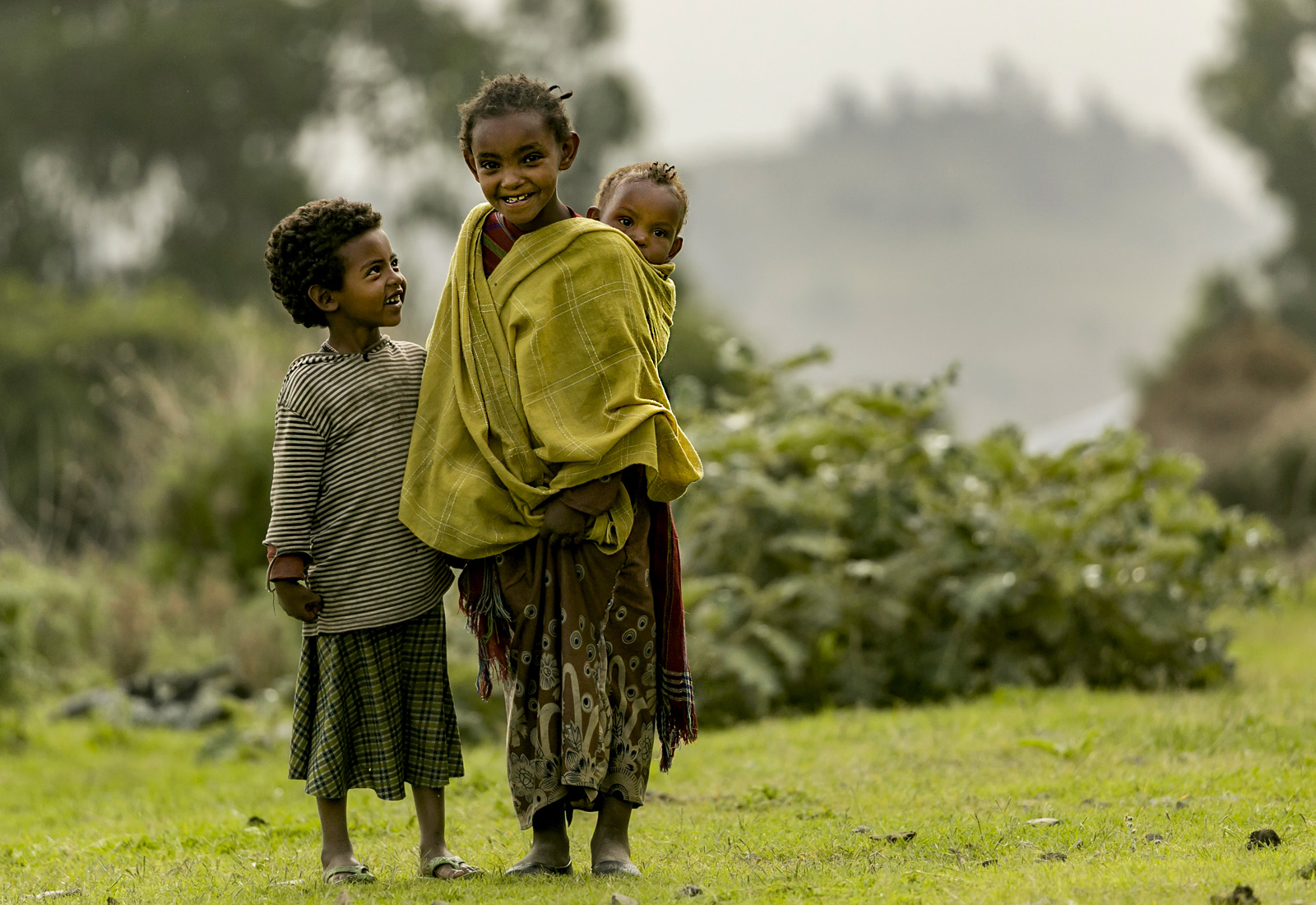 A girl with her younger sibling and friend smiles for the camera © Christian Boix