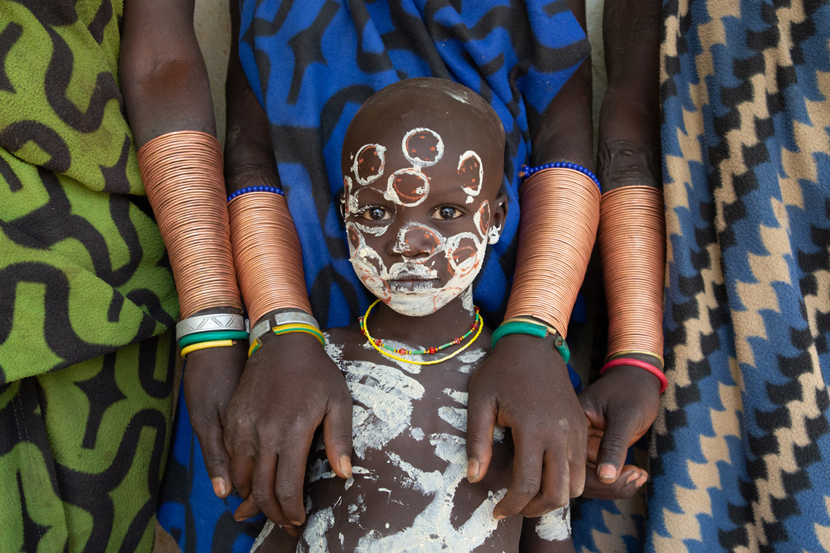 Portrait of Babuku, a young Suri boy, surrounded by the bracelets of his mother and the women of his clan in Turgit, Ethiopia © Inger Vandyke