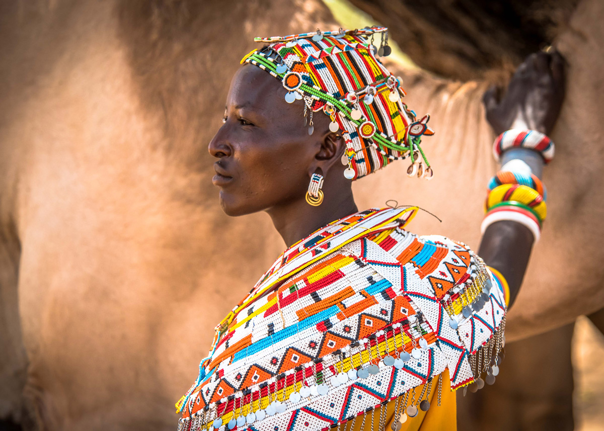 Mpayon, a Samburu woman who is one of nine Mama Tembos who patrol and help protect livestock and wildlife corridors, poses with a camel in Kalama, northern Kenya © Jane Wynyard