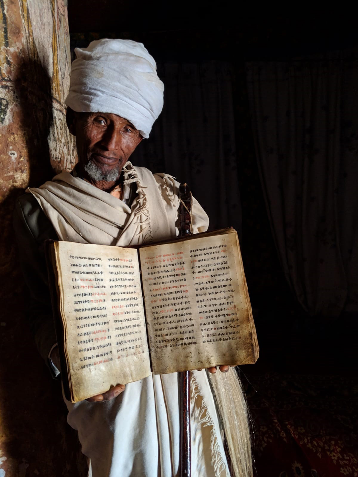 A priest holds the Bible in the Abuna Yemata Guh church, 2,580 metres above ground level. Its pages are made out of goat skin inked with Amharic letters, where the names of holy figures are written in red – Tigray Region, Ethiopia © Lukas Dennert 