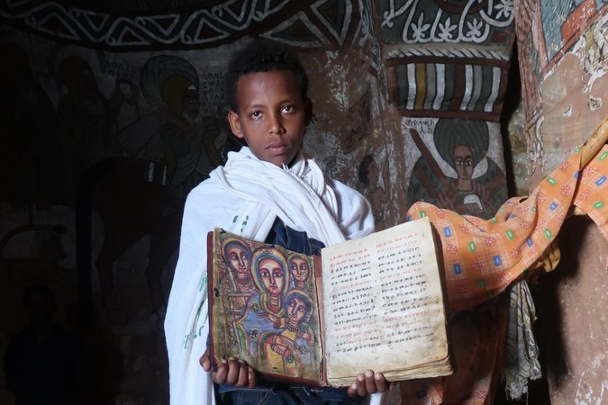 Young boy with a page from the Bible inside Abuna Yemata Guh, Tigray region, Ethiopia © Erika Atienza