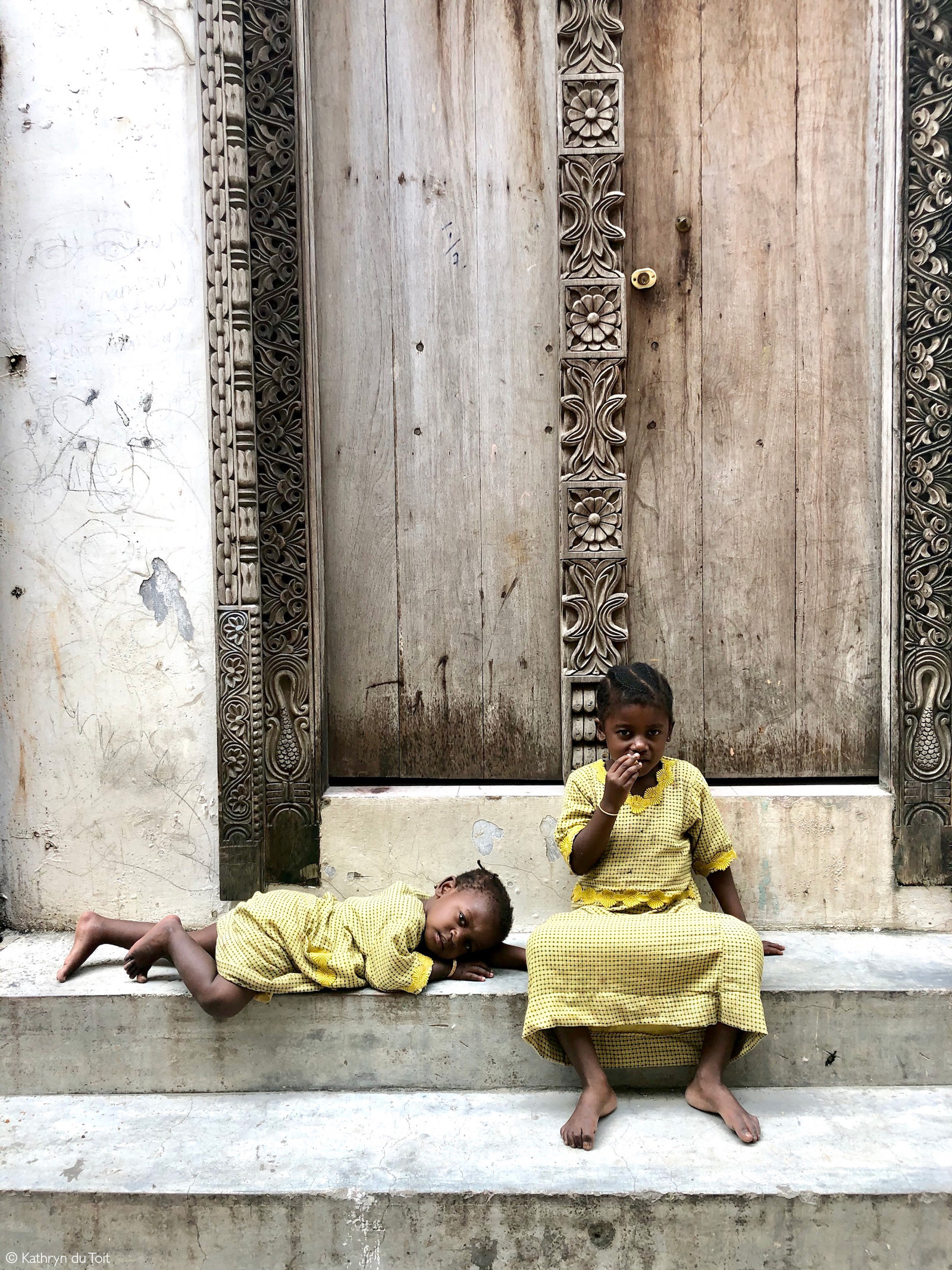 Children by a traditionally carved door. Stone Town, Zanzibar © Kathryn du Toit